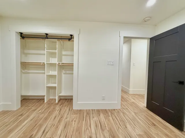 a view of an empty room with wooden floor and closet