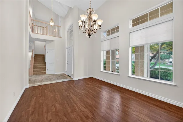 a view of an empty room with wooden floor fireplace and a window
