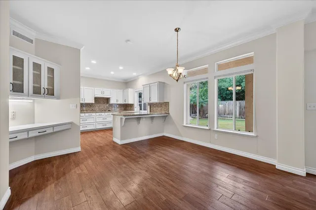 a kitchen with stainless steel appliances granite countertop a stove a sink and white cabinets with wooden floor next to windows