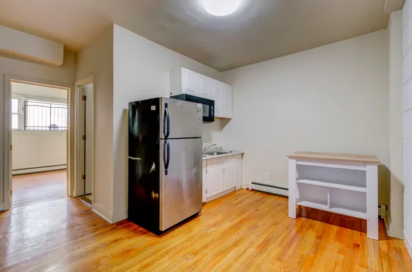 a kitchen with a refrigerator and wooden floor