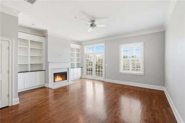 an empty room with wooden floor fireplace and windows