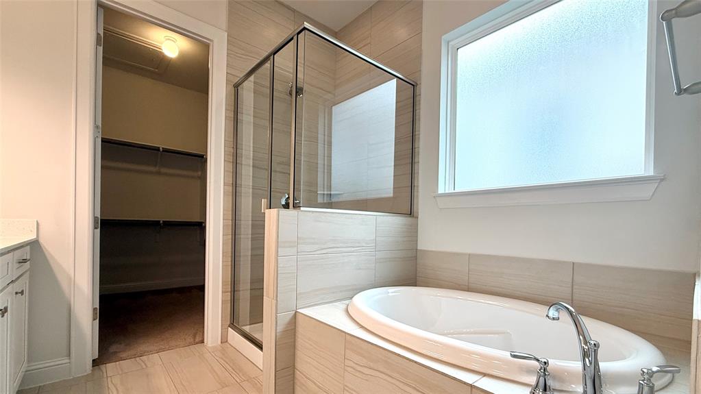 601 C-Bar Ranch Trail, Unit 27 Cedar Park, TX 78613 - Photo 23 of 29 Bathroom featuring a built-in soaking tub, glass-enclosed shower, and a frosted window