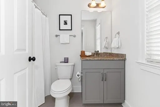 a bathroom with a granite countertop toilet sink and mirror