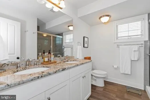 a bathroom with a granite countertop sink mirror vanity and toilet
