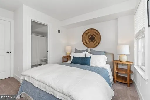 a bedroom with a bed and a lamp on dresser