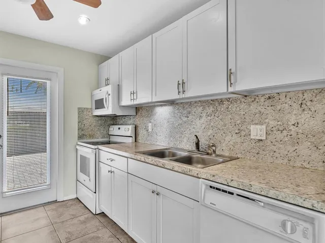 a kitchen with granite countertop white cabinets and sink