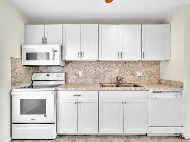 a kitchen with granite countertop white cabinets and white appliances