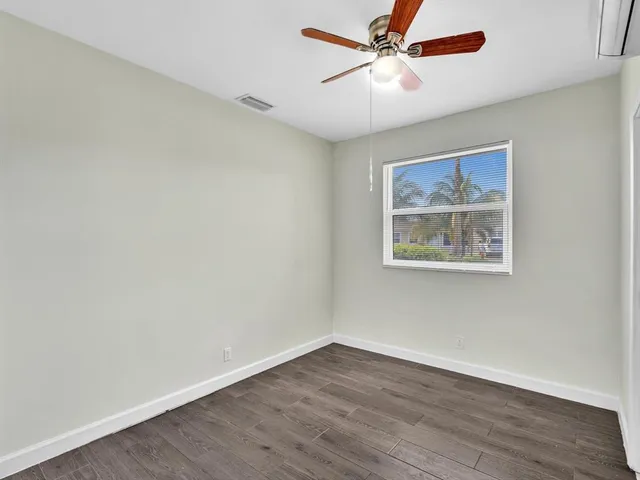 an empty room with wooden floor and ceiling fan