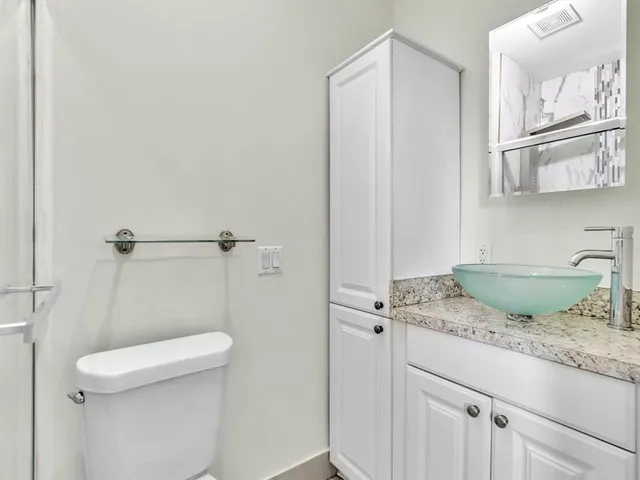 a bathroom with a granite countertop sink and a toilet