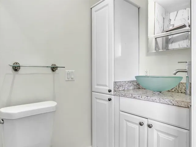 a bathroom with a granite countertop toilet and a sink