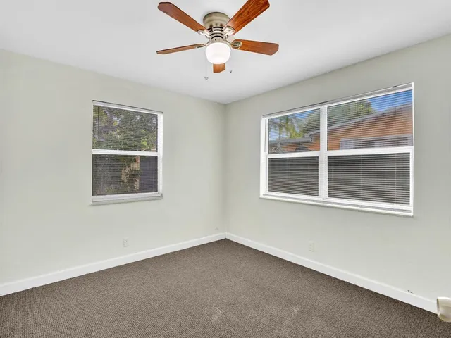 a view of an empty room with a window and a ceiling fan