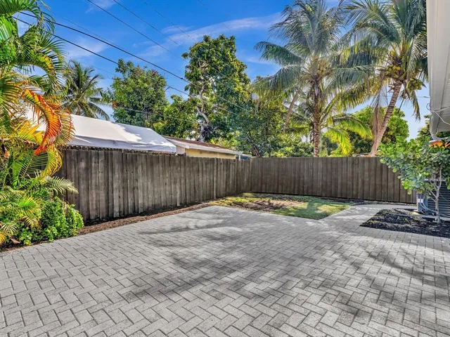 a backyard of a house with plants and trees with wooden fence