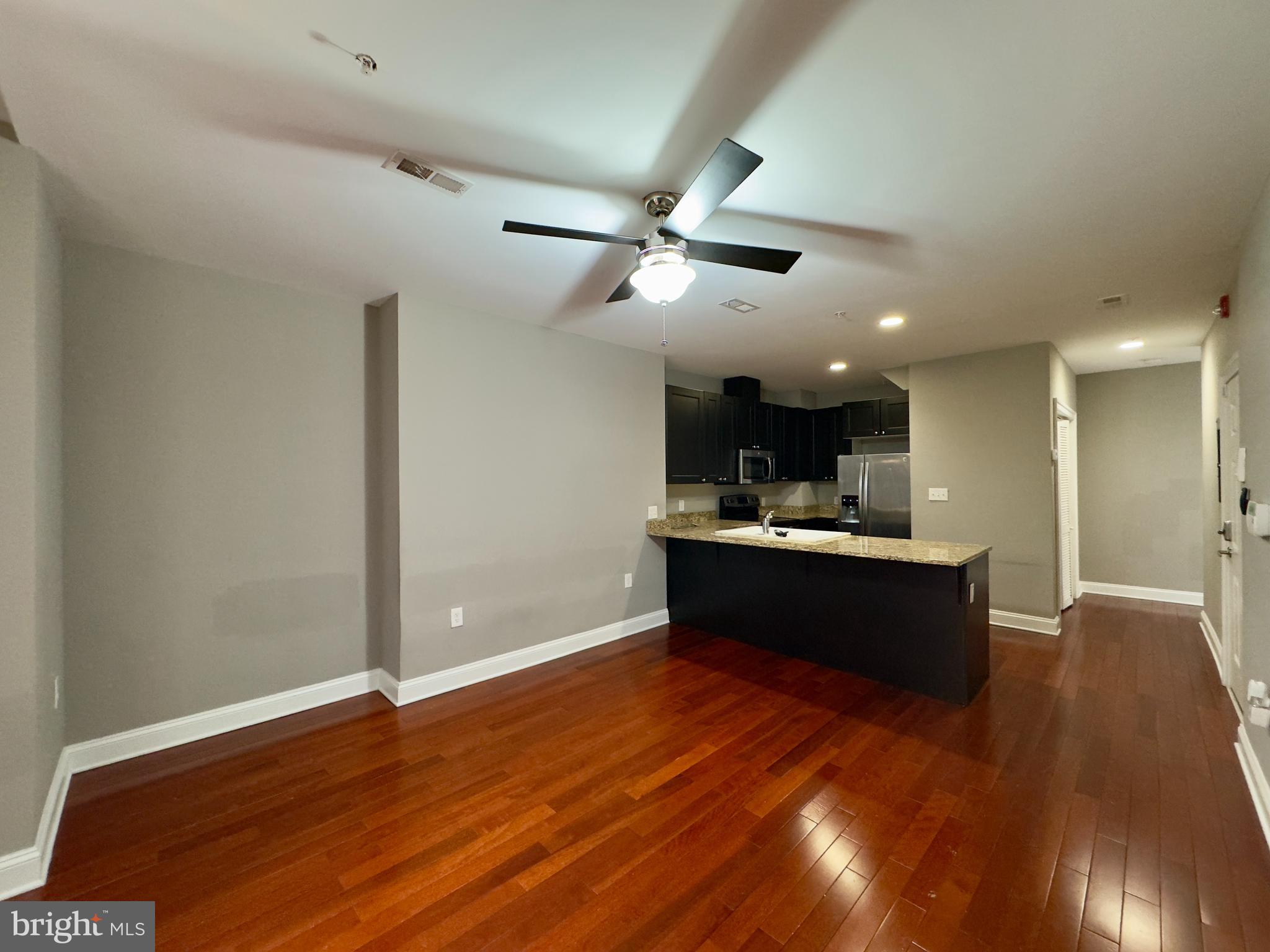 803 Cathedral Street, Unit 8 Baltimore, MD 21201 - Photo 4 of 16 a living room with stainless steel appliances kitchen island granite countertop a sink wooden floor and a large window