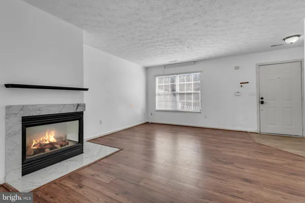 a view of an empty room with wooden floor fireplace and a window