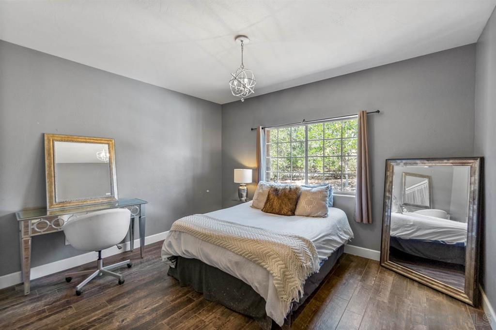 3022 Camino Del Rancho Encinitas, CA 92024 - Photo 11 of 18 a bedroom with a bed a chandelier and a window