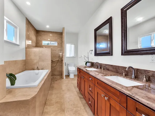 a bathroom with a granite countertop tub sink and mirror