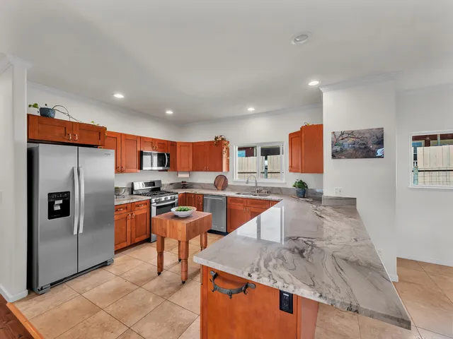 a large kitchen with stainless steel appliances kitchen island granite countertop a refrigerator a stove a sink a dining table and chairs