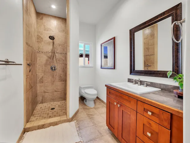 a spacious bathroom with a granite countertop sink toilet mirror and shower