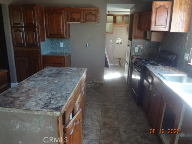 a kitchen with granite countertop a stove a sink and a refrigerator