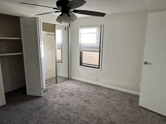 an empty room with windows and fan