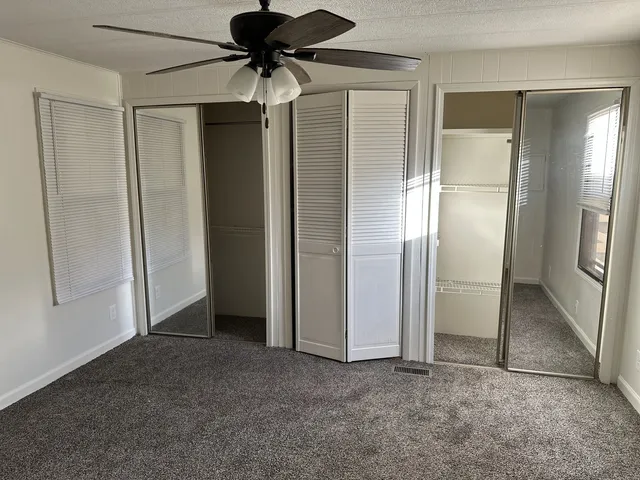 an empty room with closet and a chandelier fan