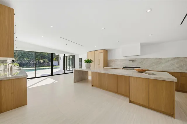 a large kitchen with stainless steel appliances a large counter top a stove and a refrigerator