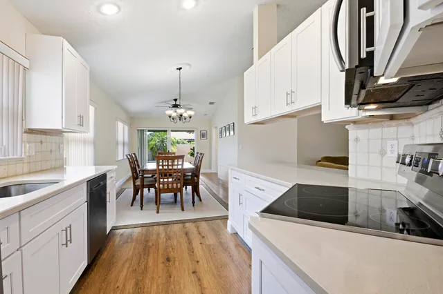 a kitchen with stainless steel appliances a stove a sink dishwasher and white cabinets with wooden floor