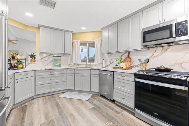 a kitchen with cabinets stainless steel appliances and wooden floor