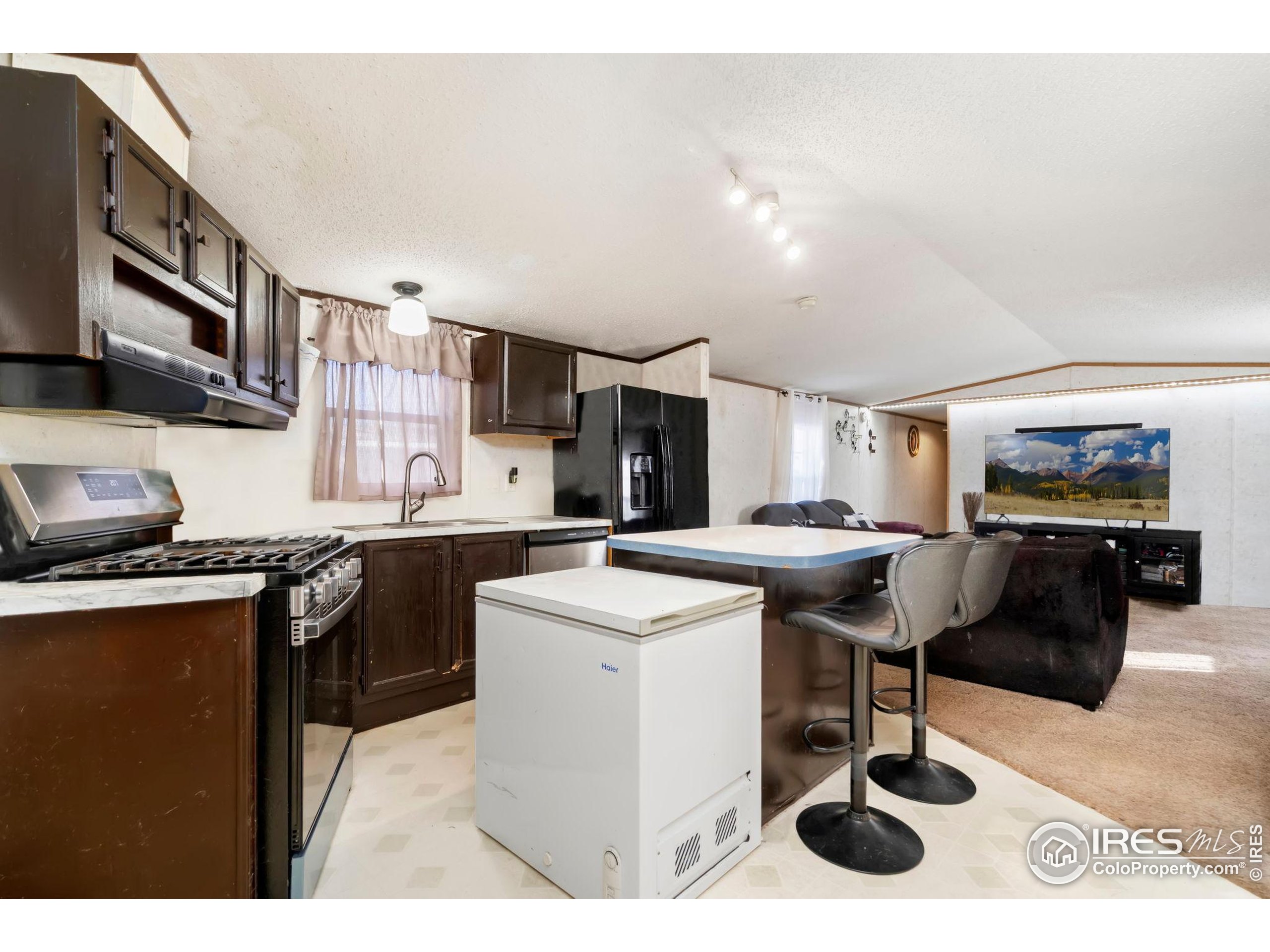 2500 East Harmony Road, Unit 166 Fort Collins, CO 80528 - Photo 6 of 24 a kitchen with stainless steel appliances kitchen island granite countertop a sink dishwasher a stove a dining table and chairs with wooden floor