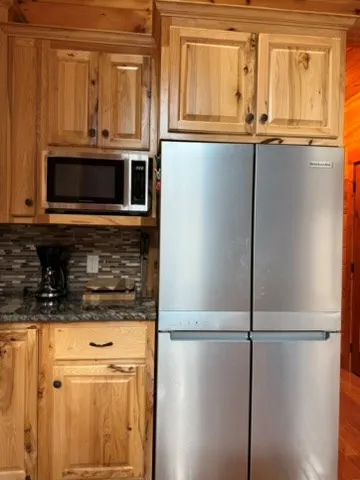 a kitchen with stainless steel appliances granite countertop a refrigerator a microwave and cabinets