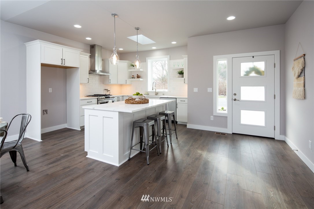 5578 South Church Road Ferndale, WA 98248 - Photo 14 of 36 a open kitchen with stainless steel appliances granite countertop a stove top oven a refrigerator a dining table and chairs with wooden floor