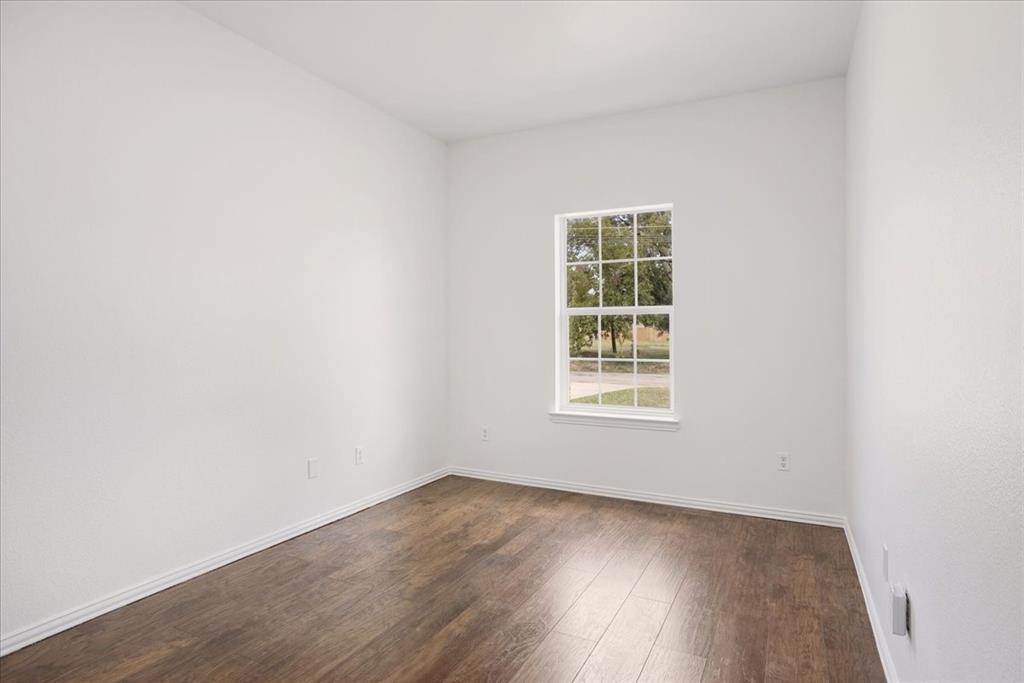 700 East 6th Street Bonham, TX 75418 - Photo 22 of 28 an empty room with wooden floor and windows