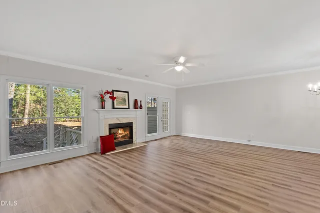 a view of an empty room with wooden floor fireplace and a window