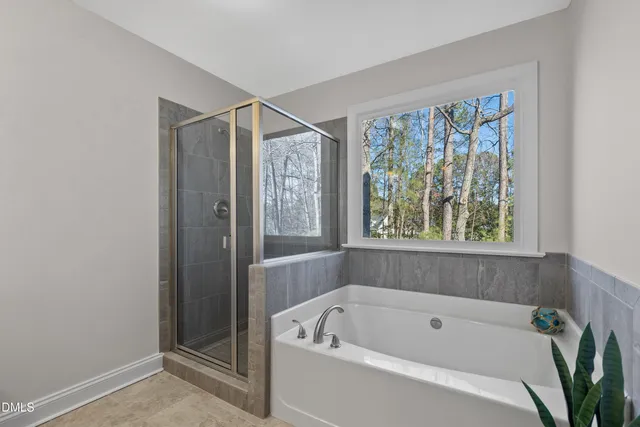 a bathroom with a tub a window and shower