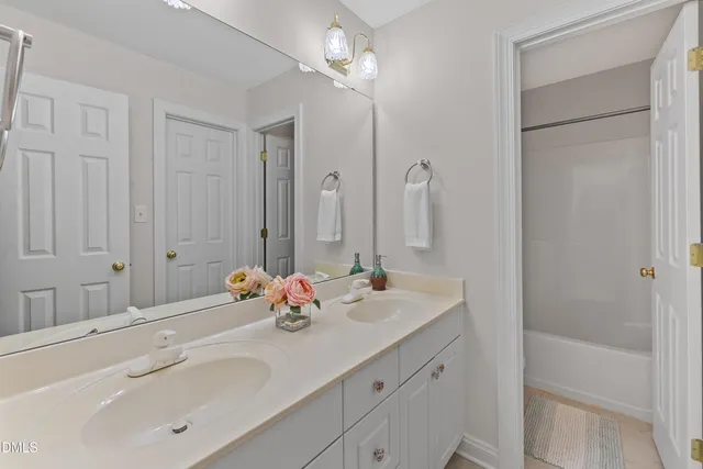 a bathroom with a double vanity sink a mirror and a bathtub