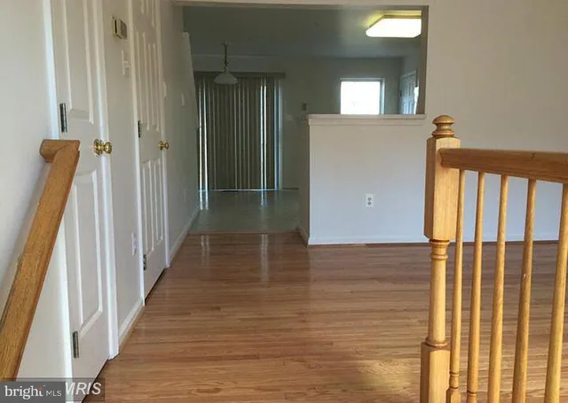 a view of a hallway with wooden floor and staircase