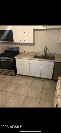a view of kitchen with granite countertop lots of white stainless steel appliances