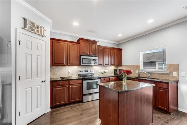 a kitchen with stainless steel appliances granite countertop a sink stove refrigerator and cabinets