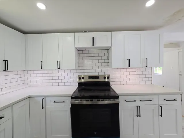 a kitchen with granite countertop white cabinets and a stove
