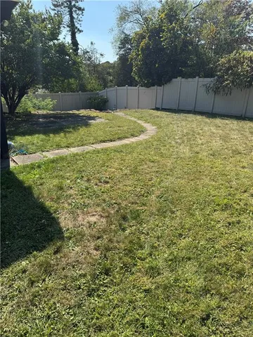 a view of a small house with yard and a large parking space