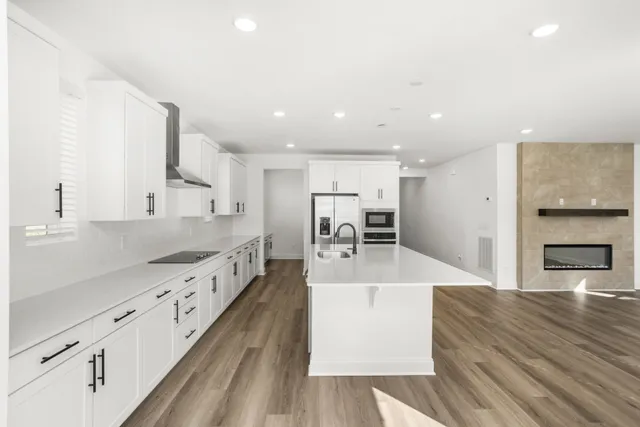 a large kitchen with a center island wooden floor stainless steel appliances and cabinets