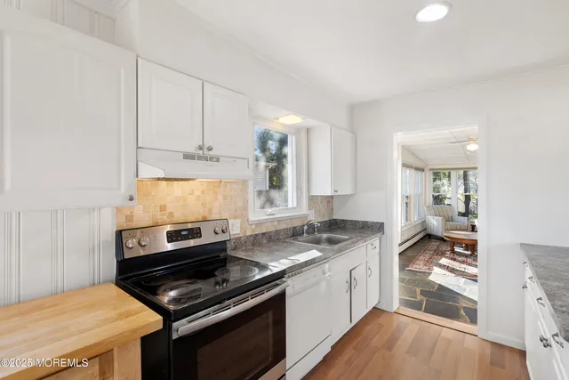 a kitchen with a stove a sink and wooden floor