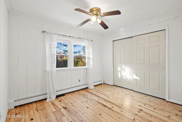 a view of empty room with wooden floor and fan