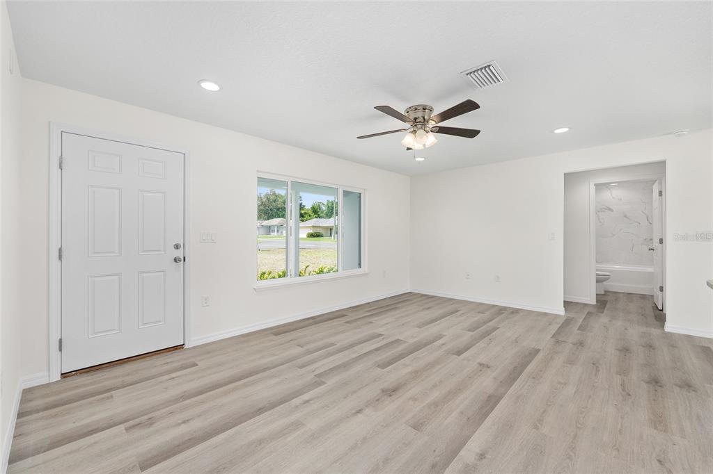 13019 Northeast 7th Loop Silver Springs, FL 34488 - Photo 10 of 35 an empty room with wooden floor and ceiling fan