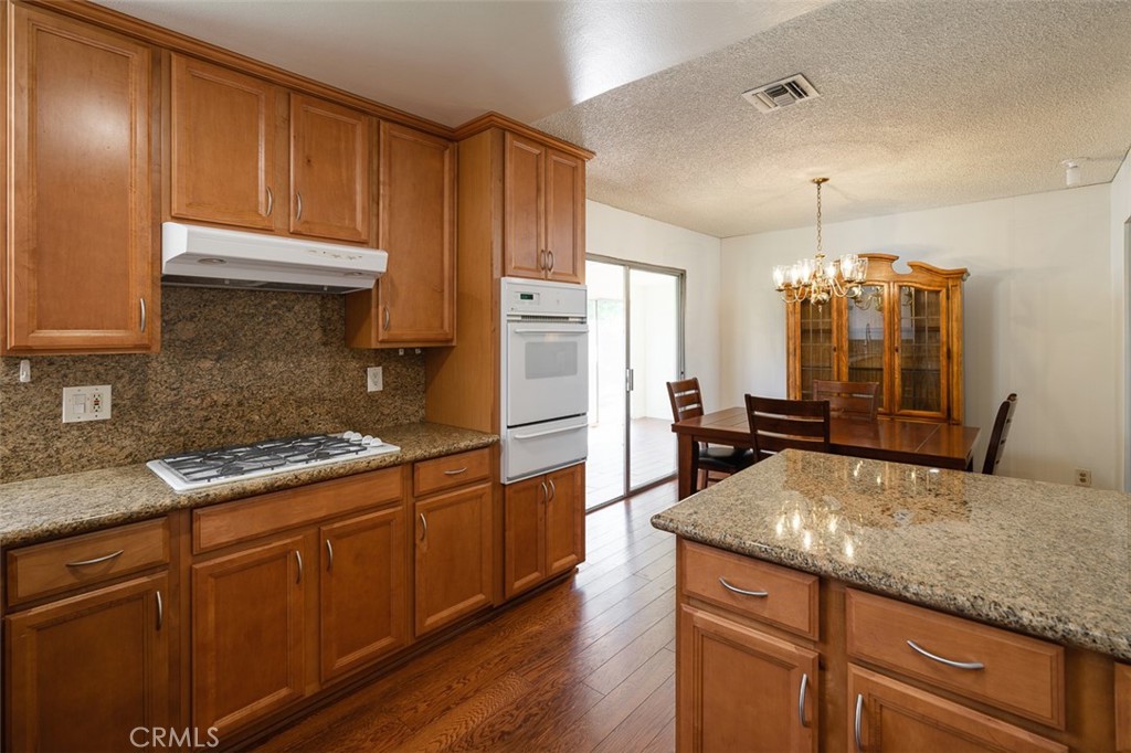 9716 Loftus Drive Rosemead, CA 91770 - Photo 12 of 28 a kitchen with kitchen island granite countertop wooden cabinets and a refrigerator