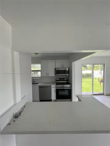 a kitchen with a stove a microwave and a window