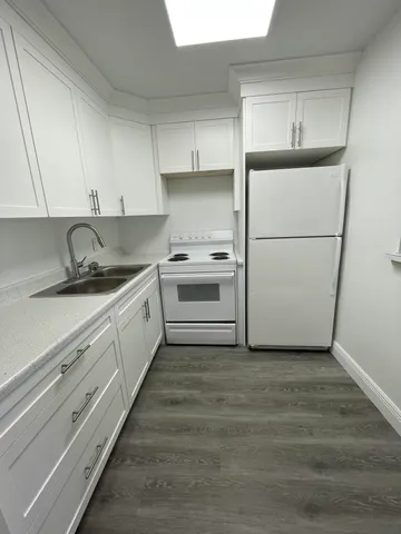 a kitchen with granite countertop white cabinets and white appliances