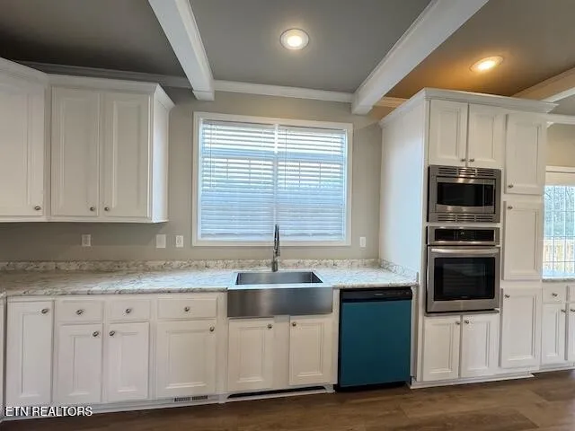 a kitchen with granite countertop a sink stainless steel appliances and white cabinets