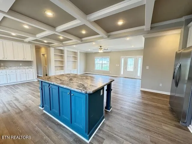 an open kitchen with kitchen island wooden floor center island and stainless steel appliances