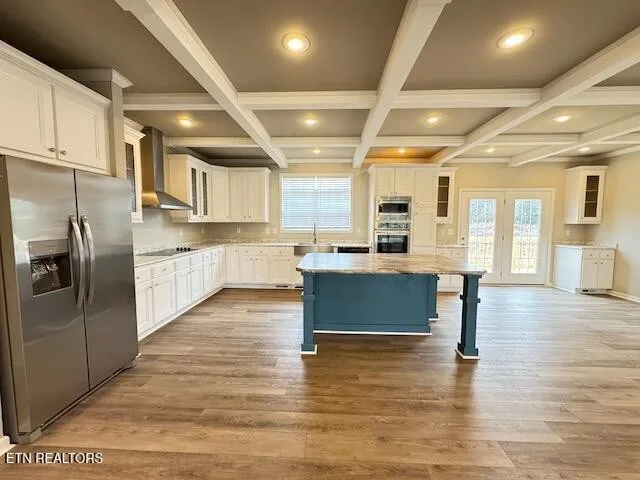 a large kitchen with stainless steel appliances kitchen island granite countertop a large kitchen island a stove a refrigerator a sink and a dining table with wooden floors